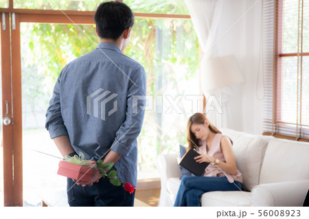 asian couple with man hiding red rose and gift box asian couple with man hiding red rose and gift box 56008923