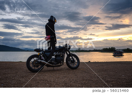 Biker standing on vintage big bike with sky at 56015460