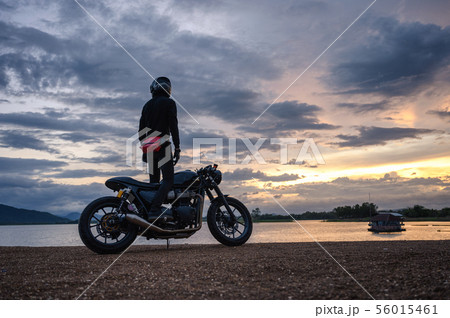 Biker standing on vintage big bike with sky at 56015461