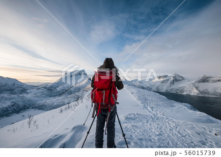 Mountaineer with backpack taking a photo a scenery Mountaineer with backpack taking a photo a scenery 56015739