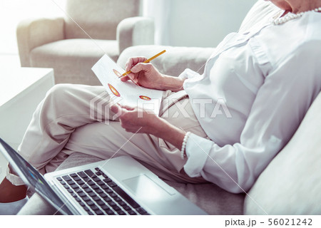Stylish retired woman wearing nice accessories holding pencil in her hand Stylish retired woman wearing nice accessories holding pencil in her hand 56021242