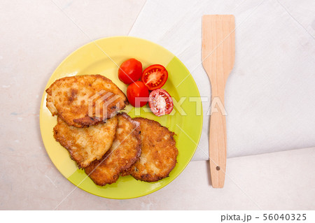 Potato pancakes with meat and tomatoes on green 56040325