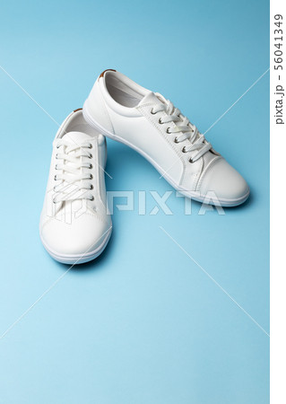 Pair of white sneakers on blue background. Fashion Pair of white sneakers on blue background. Fashion 56041349