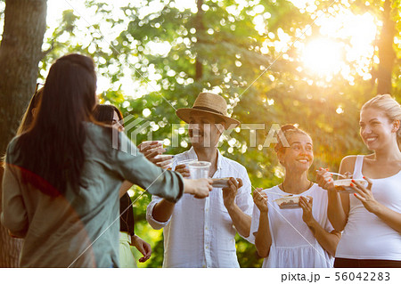 Happy friends eating and drinking beers at barbecue dinner on sunset time 56042283