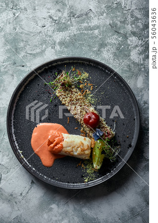 Black cod steak with tomato sauce and buckwheat popcorn, top view on a plate. Copy space, gray 56043636