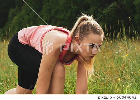 young woman in low start position before jogging 56044043