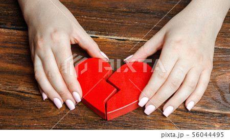 A woman collects a broken heart in his hands. A woman collects a broken heart in his hands. 56044495