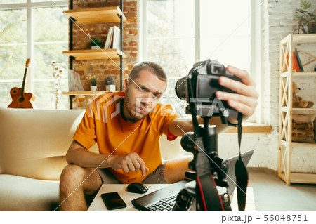Caucasian male blogger with camera recording video review of gadgets at home 56048751