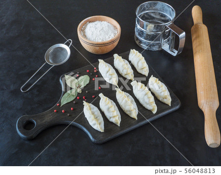 Frozen uncooked dumplings on a black board. Frozen uncooked dumplings on a black board. 56048813