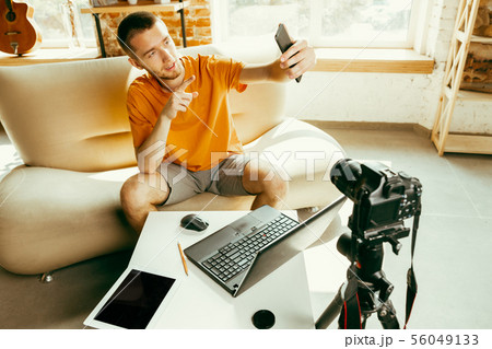 Caucasian male blogger with camera recording video review of gadgets at home 56049133
