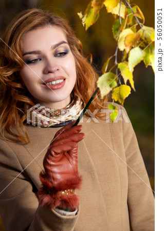 Beautiful woman with palette and brush paints colors leaves on the trees Beautiful woman with palette and brush paints colors leaves on the trees 56050051