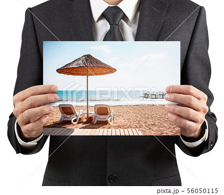 Businessman holds placard with photo of vacation scenery. Businessman holds placard with photo of vacation scenery. 56050115