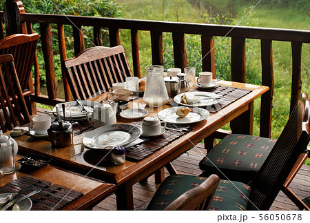 Wooden desk after morning breakfast - remains on plates and coffee cups, butts in ashtray, half 56050678