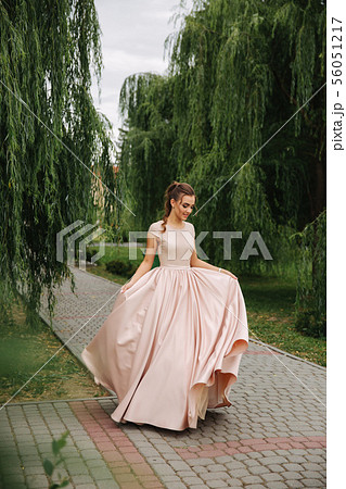 Fashionable girl spin around in park. Evening dress 56051217