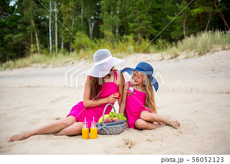 Mom with a daughter on the beach drink juice. Mom with a daughter on the beach drink juice. 56052123