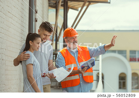 Foreman or achitect shows house, office or store design plans to a young couple 56052809