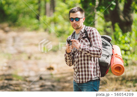 Hipster young man with backpack using smart phone on beautiful nature.Travel concept. Outdoor travel 56054209