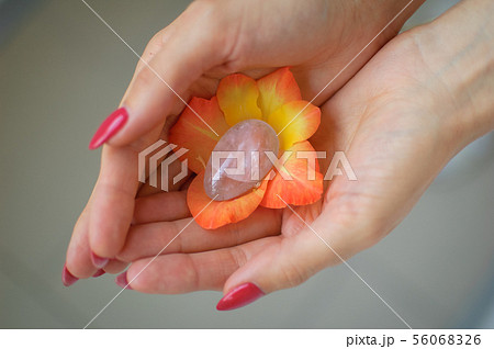 Female hand with red manicure holding transparent violet amethyst yoni egg for vumfit, imbuilding or 56068326