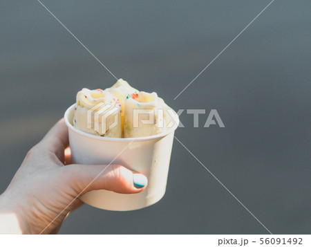 Hand holding rolled ice cream in cone cup Hand holding rolled ice cream in cone cup 56091492