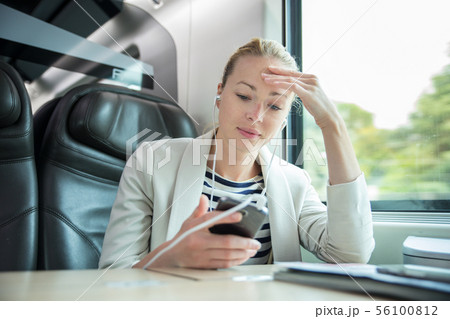 Businesswoman communicating on mobile phone while traveling by train. Businesswoman communicating on mobile phone while traveling by train. 56100812