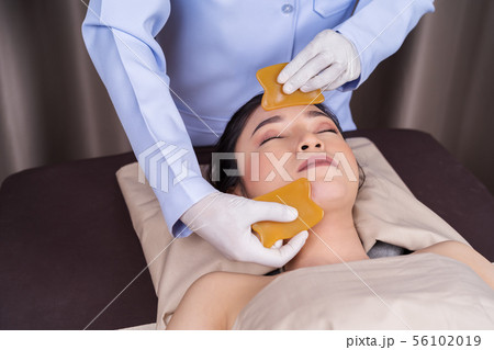 woman receiving traditional guasa face therapy woman receiving traditional guasa face therapy 56102019