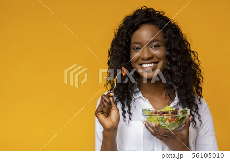 Happy african american woman eating vegetable salad Happy african american woman eating vegetable salad 56105010