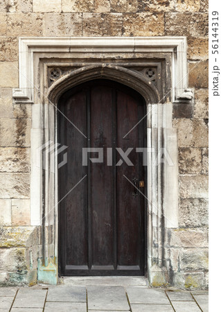 Closed black wooden door in old stone wall 56144319