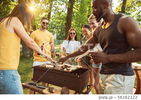 Happy friends are having beer and barbecue party at sunny day 56162122