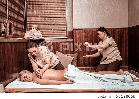 Two masseuses working in team massaging their client. 56188059