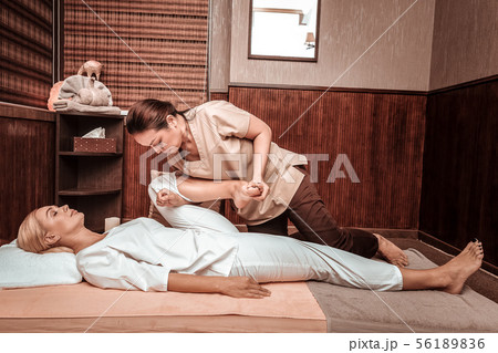 Strong masseuse doing thai massage for her client. Strong masseuse doing thai massage for her client. 56189836