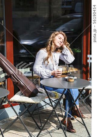 Girl dreams sitting with coffee and violin in cafe 56190454
