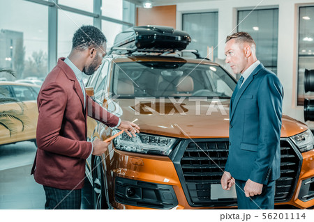 Car dealer showing his client suitable automobile. 56201114