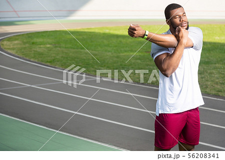 Calm young muscular man standing at the stadium Calm young muscular man standing at the stadium 56208341