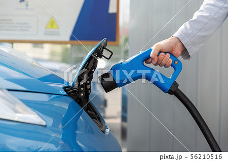 A man charging his electric car at charging station A man charging his electric car at charging station 56210516