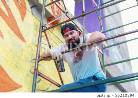 Graffiti artist painting with aerosol spray bottle 56210594