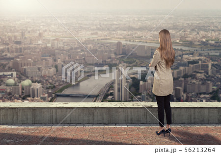 A businesswoman standing on roof looking at city A businesswoman standing on roof looking at city 56213264