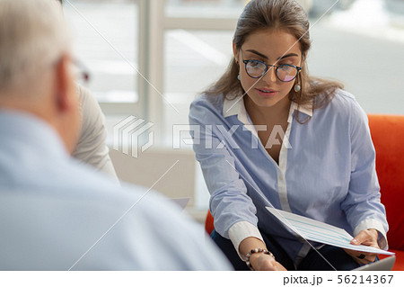 Attentive brunette woman looking at pale of documents Attentive brunette woman looking at pale of documents 56214367