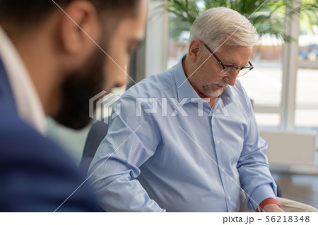 Serious grey-haired male person checking data on document Serious grey-haired male person checking data on document 56218348