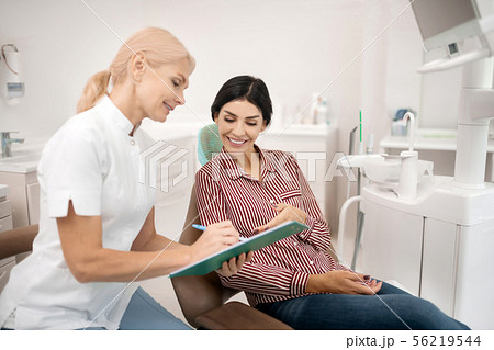 Patient telling her dentist information about herself. Patient telling her dentist information about herself. 56219544