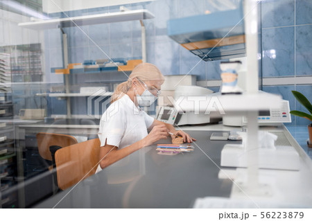 Dental technician working on porcelain prosthesis in her laboratory. Dental technician working on porcelain prosthesis in her laboratory. 56223879
