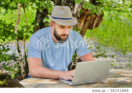 Businessman works with computer in forest. Businessman works with computer in forest. 56241866