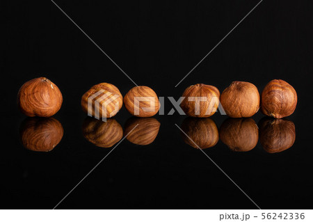 Ripe brown hazelnut isolated on black glass Ripe brown hazelnut isolated on black glass 56242336