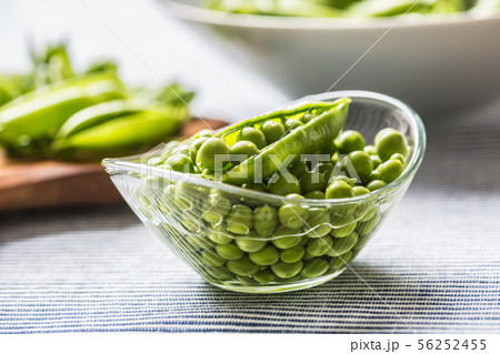 Fresh green pea seeds in bowl on kitchen table 56252455