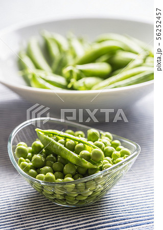 Fresh green pea seeds in bowl on kitchen table 56252457