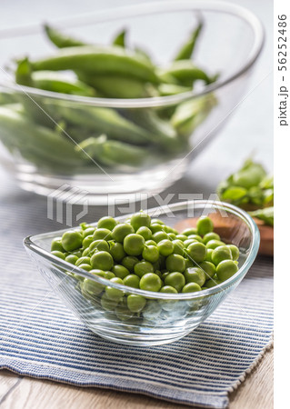 Fresh green pea seeds in bowl on kitchen table 56252486