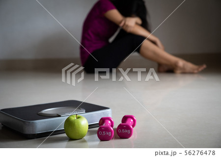 Close up weighing Scale in front of upset woman 56276478