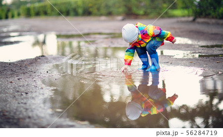 Child walking in wellies in puddle on rainy weather 56284719