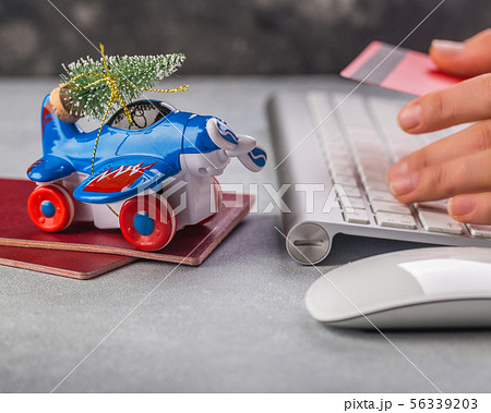 Small airplane with christmas tree, passports, keybaord, credit card on grey background. Vacation 56339203