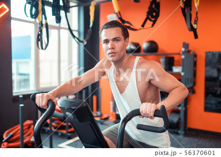 Handsome serious man sitting on the sports machine Handsome serious man sitting on the sports machine 56370601