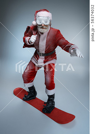 Mature Santa Claus holding sack, standing on snowboard 56374032